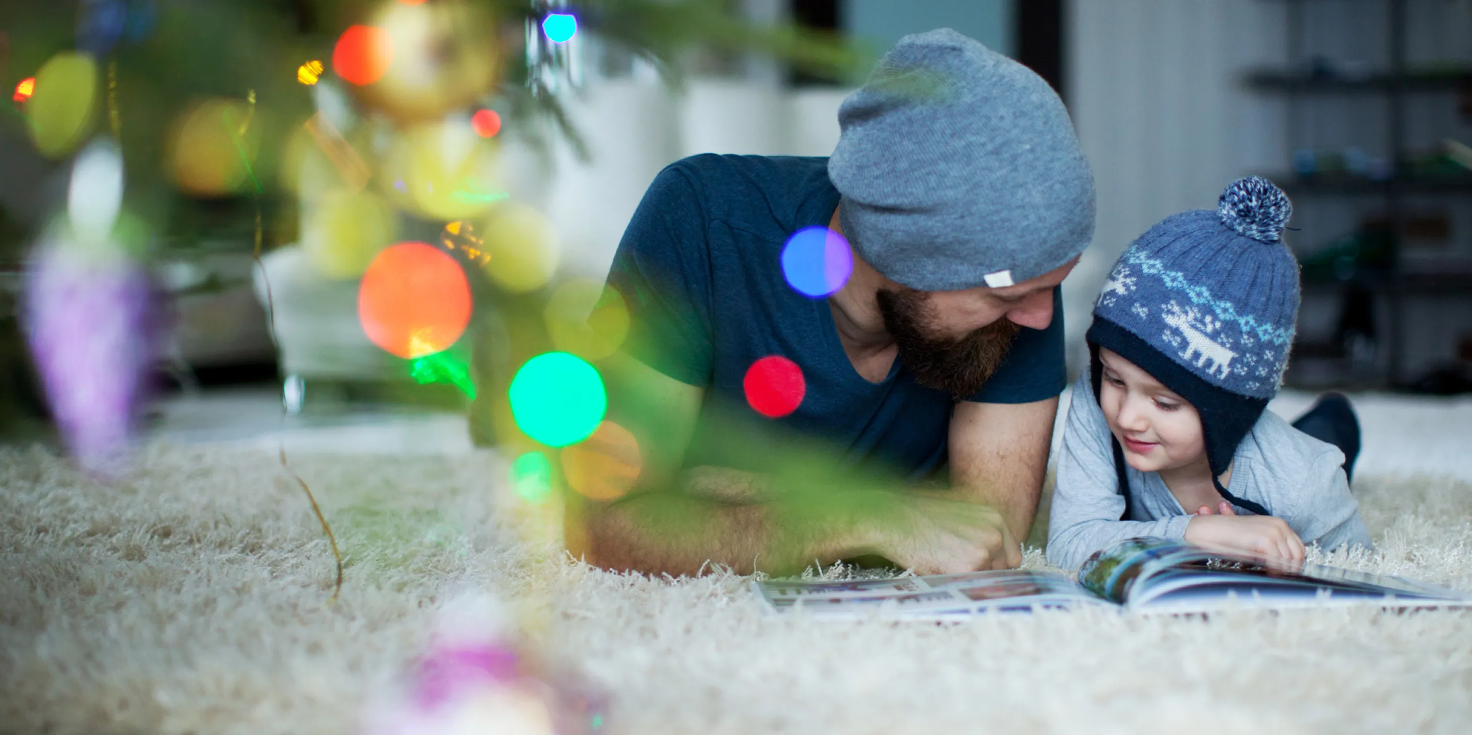 Vater und Sohn lesen unter dem Weihnachtsbaum